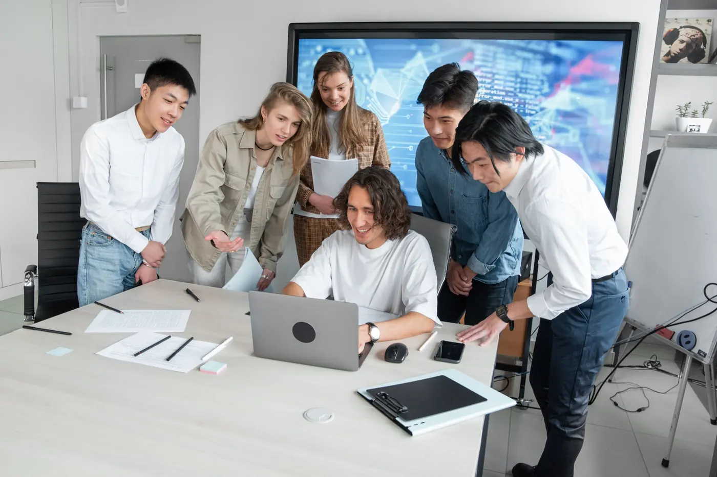 Ein Kollege zeigt dem Team etwas am Laptop