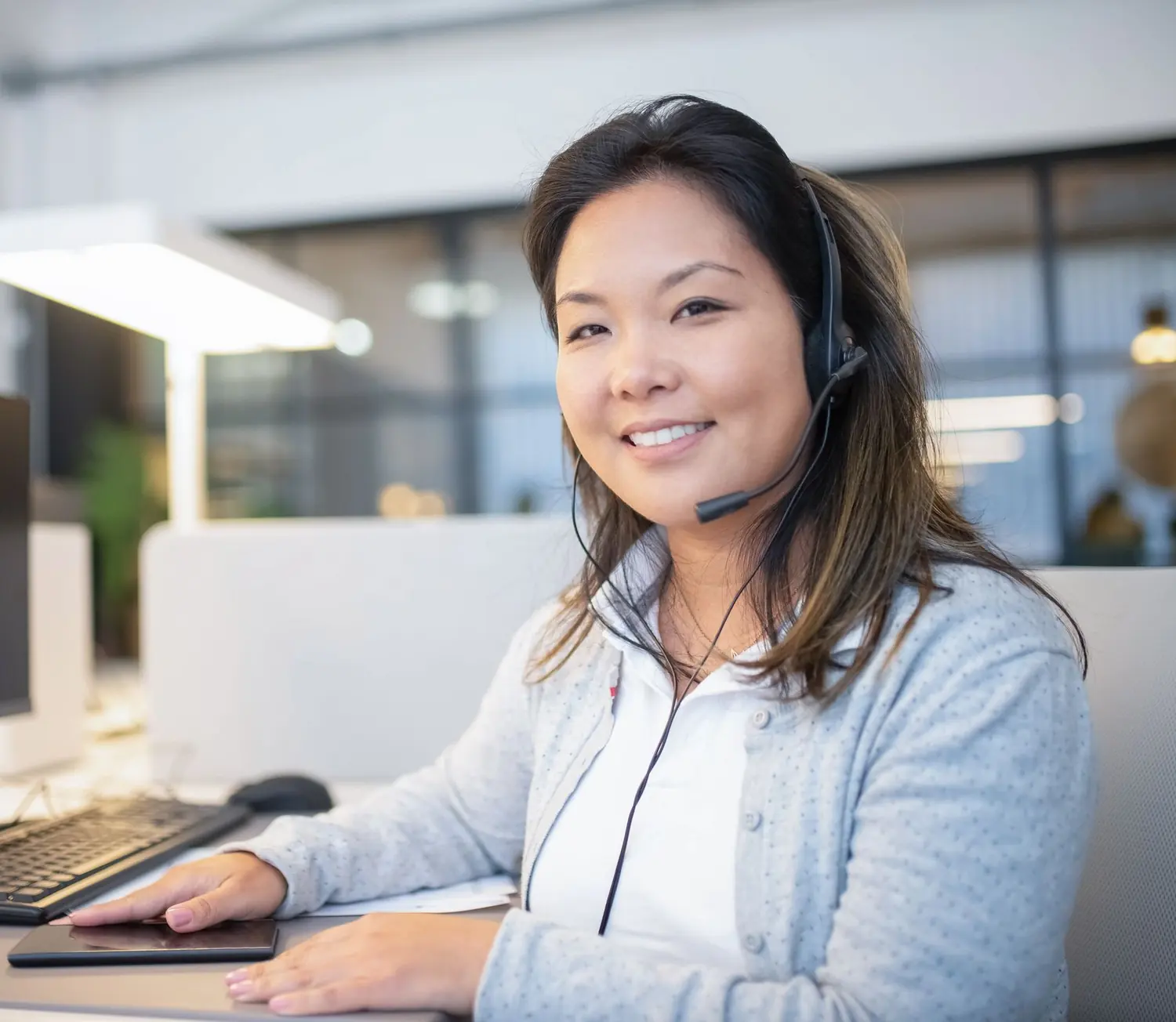 Kundenservice-Mitarbeiterin mit Headset lächelt in die Kamera