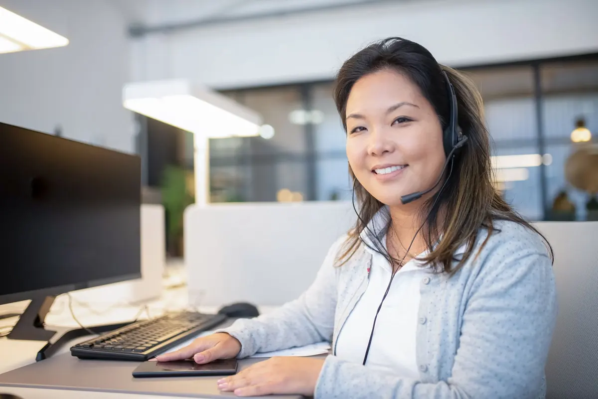 Kundenservice-Mitarbeiterin mit Headset am Arbeitsplatz
